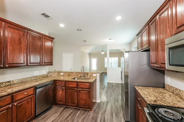 a kitchen with stainless steel appliances granite countertop wooden cabinets a stove top oven a sink and dishwasher