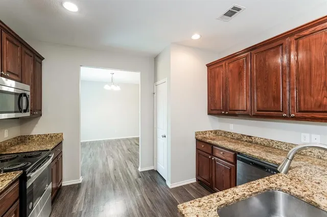 a kitchen with granite countertop wooden cabinets and a stove top oven