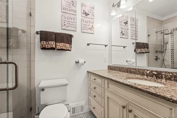 a bathroom with a granite countertop sink a mirror a toilet and a shower