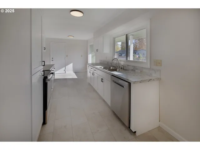 a kitchen with stainless steel appliances kitchen island granite countertop a refrigerator a stove and white cabinets