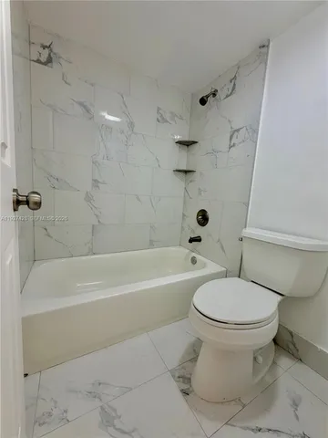 a white toilet sitting next to a bath tub and a shower