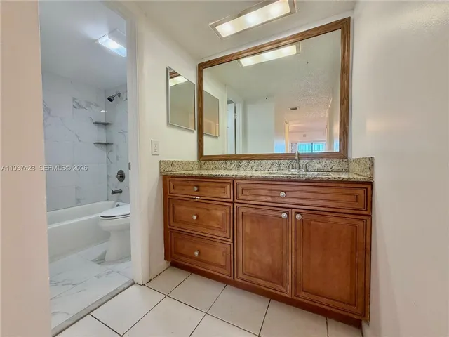 a spacious bathroom with a granite countertop sink a toilet mirror and bathtub
