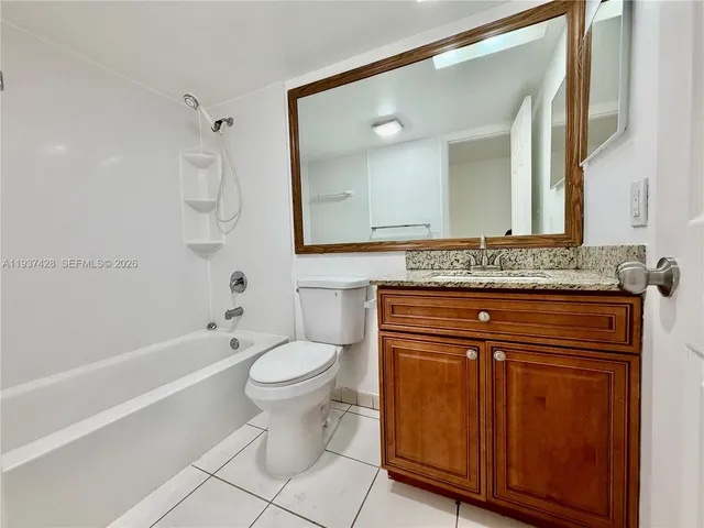 a bathroom with a granite countertop toilet sink and mirror