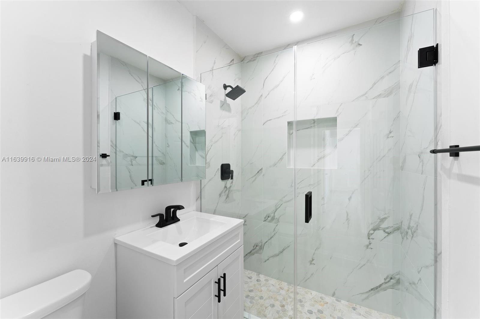 3155 Southwest 27th Lane, Unit 1 Miami, FL 33133 - Photo 11 of 18 a bathroom with a sink a toilet a mirror and shower