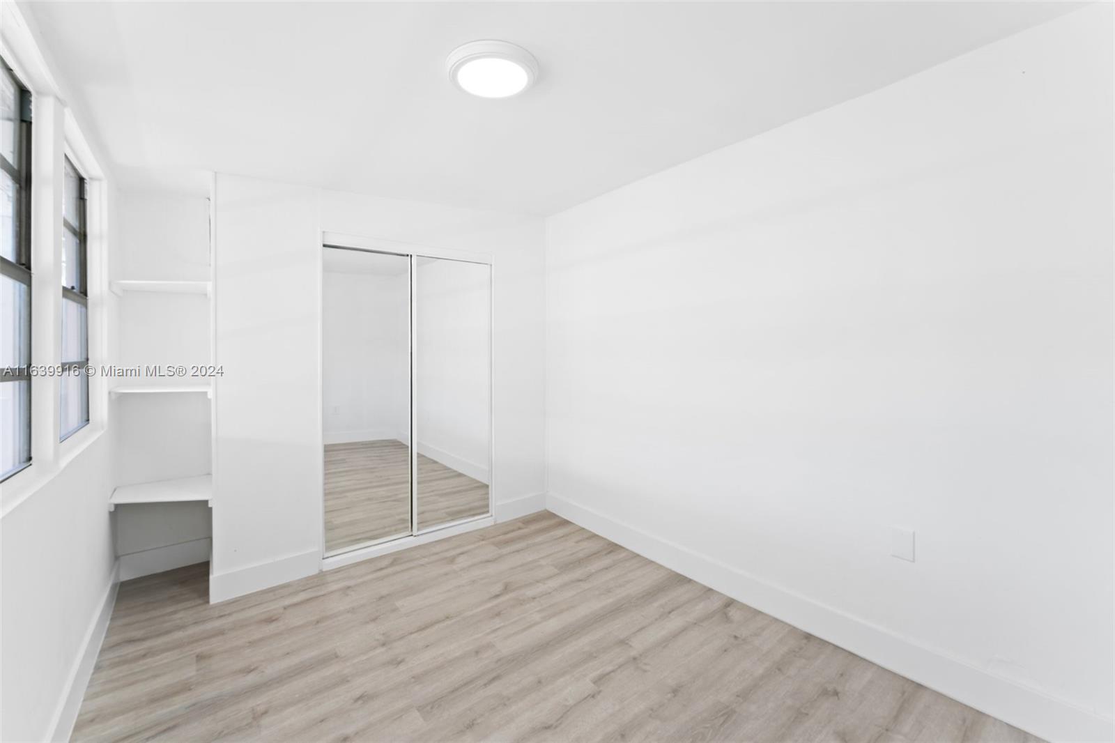 3155 Southwest 27th Lane, Unit 1 Miami, FL 33133 - Photo 15 of 18 a view of an empty room with wooden floor and a window