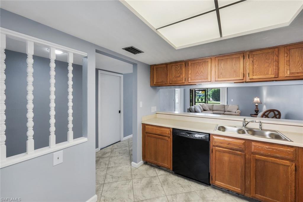 5857 Rattlesnake Hammock Road, Unit 101 Naples, FL 34113 - Photo 8 of 19 Kitchen featuring wood cabinetry, a double basin stainless steel sink, black dishwasher, and laminate countertops