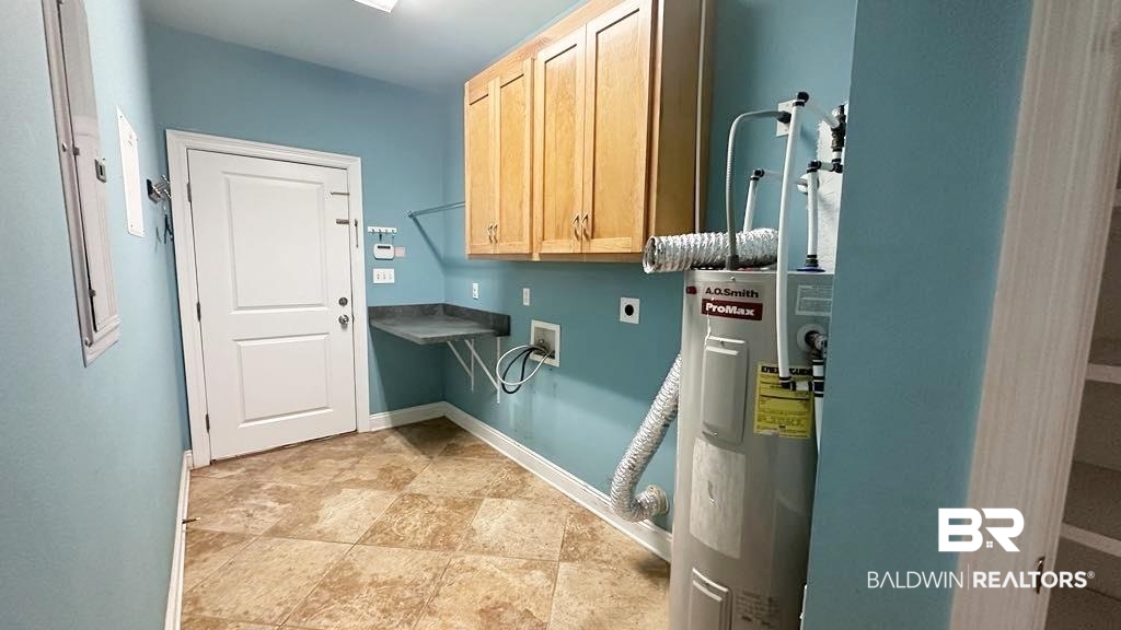 23289 McPhillips Road Loxley, AL 36551 - Photo 11 of 19 Utility room featuring checkerboard tile flooring, upper cabinetry with wood-finish doors, a folding countertop, and an exterior door