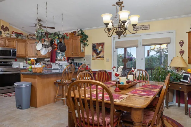 a view of a dining room with furniture a chandelier and large windows