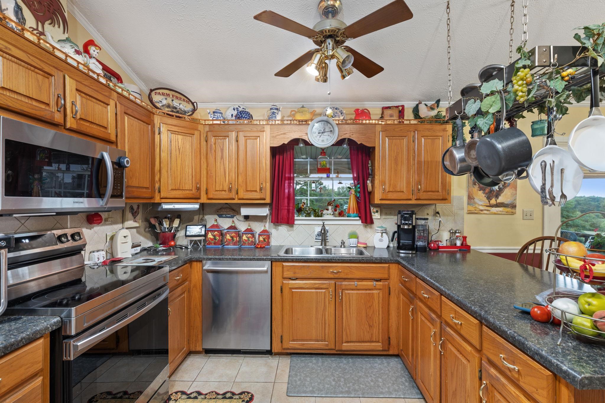 116 County Road 713 Corinth, MS 38834 - Photo 29 of 40 Kitchen with stainless steel appliances, brown cabinetry, a peninsula, dark countertops, and ornamental molding