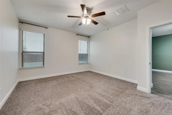 an empty room with windows and fan