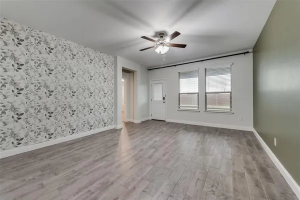 a view of empty room with wooden floor and fan