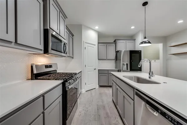 a kitchen with stainless steel appliances granite countertop a sink a stove and a refrigerator