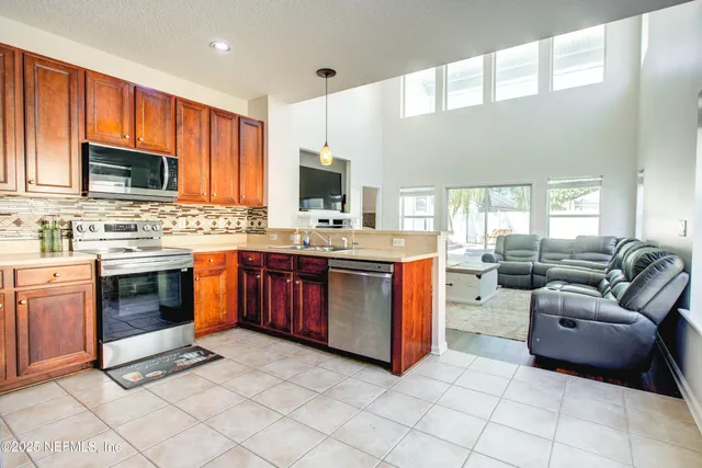 a kitchen with stainless steel appliances granite countertop a stove top oven a sink dishwasher a dining table and chairs with wooden floor