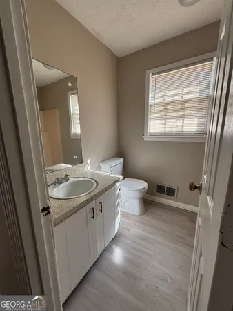 a bathroom with a granite countertop sink toilet and mirror
