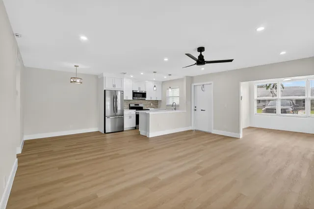 a view of an empty room with a window and wooden floor