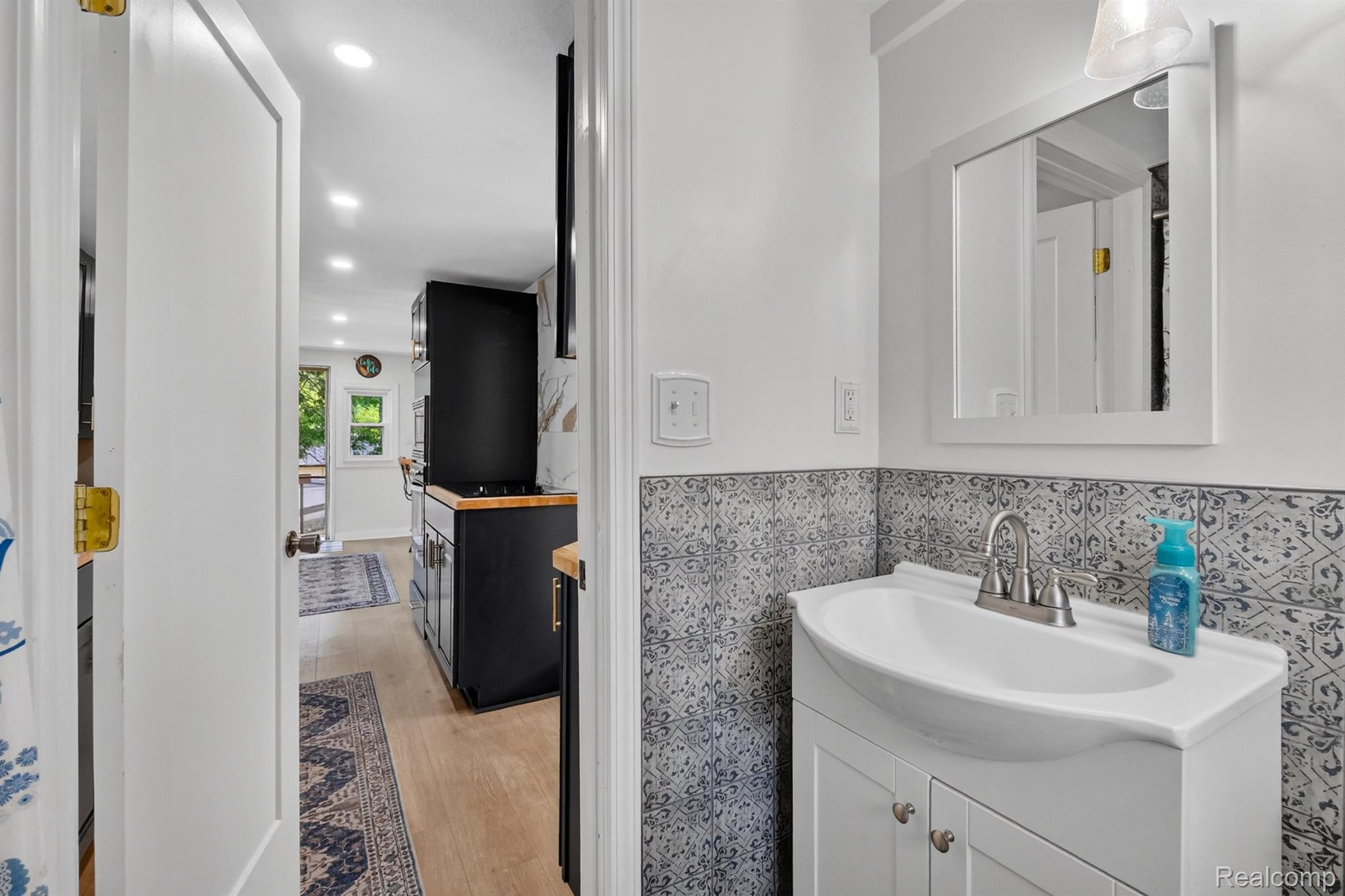 1717 Triangle Lake Road Howell, MI 48843 - Photo 49 of 58 Bathroom featuring a white vanity with an integrated sink, patterned wall tile, and a framed mirror