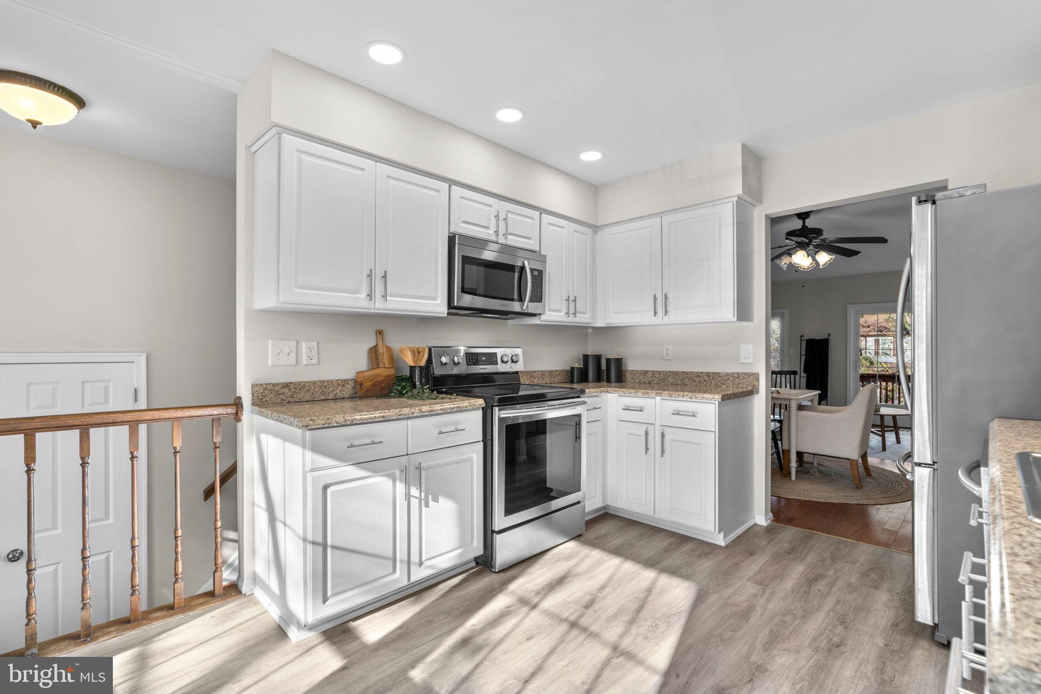 7525 Swan Point Way, Unit 195 Columbia, MD 21045 - Photo 12 of 30 a kitchen with granite countertop a stove top oven a sink dishwasher and a refrigerator with wooden floor
