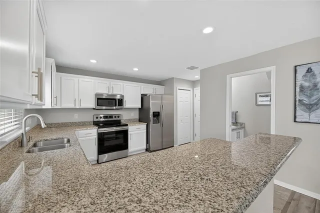 a kitchen with granite countertop white cabinets and a sink