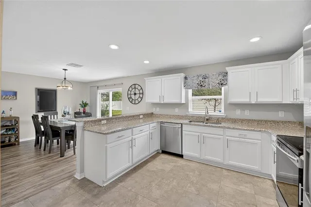a kitchen with stainless steel appliances granite countertop white cabinets a sink and a stove
