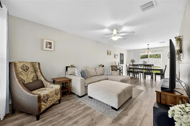 a view of a dining room and livingroom with furniture wooden floor a rug a painting and a chandelier