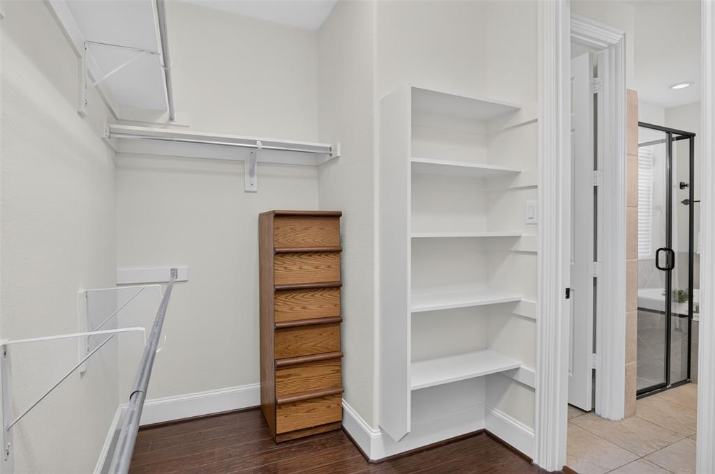 842 Sun Meadow Road Allen, TX 75013 - Photo 17 of 39 Organized closet featuring multiple hanging rods, overhead shelving, built-in shelving, and dark wood-finish flooring