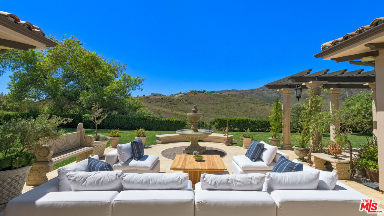 27311 Winding Way Malibu, CA 90265 - Photo 13 of 73 a view of a patio with couches chairs potted plants and a palm tree