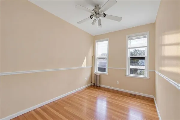 an empty room with wooden floor fan and windows