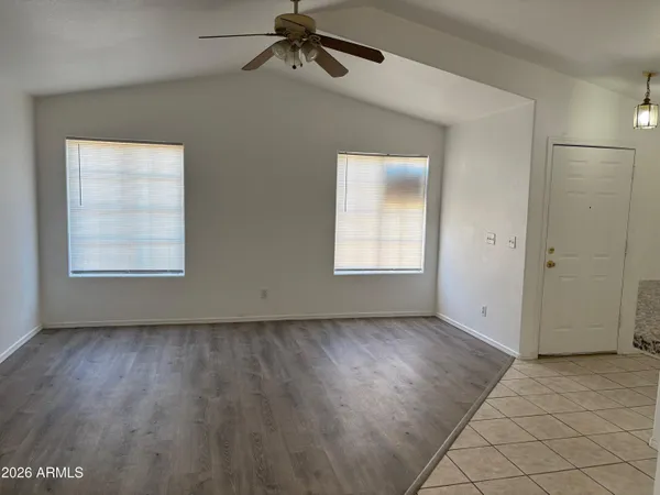 an empty room with wooden floor cabinet and windows