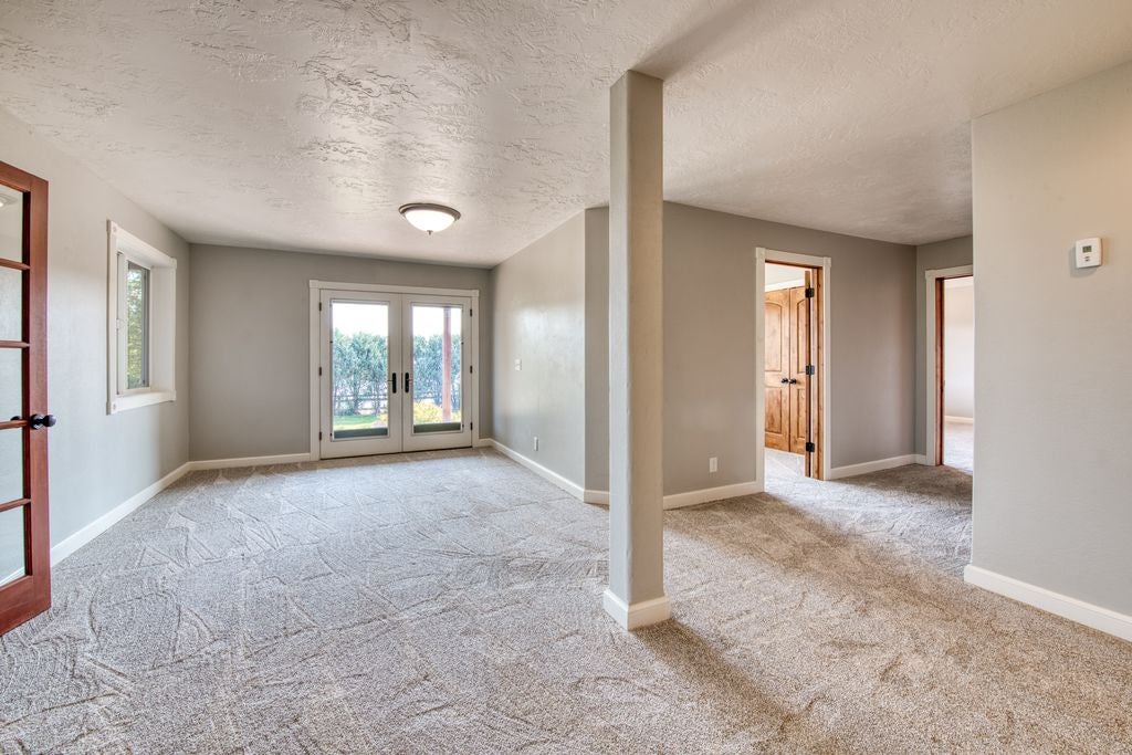 16374 Folsom Road Florence, MT 59833 - Photo 85 of 98 Unfurnished room featuring french doors, a textured ceiling, and light colored carpet