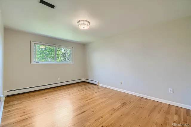 a view of an empty room with wooden floor and a window