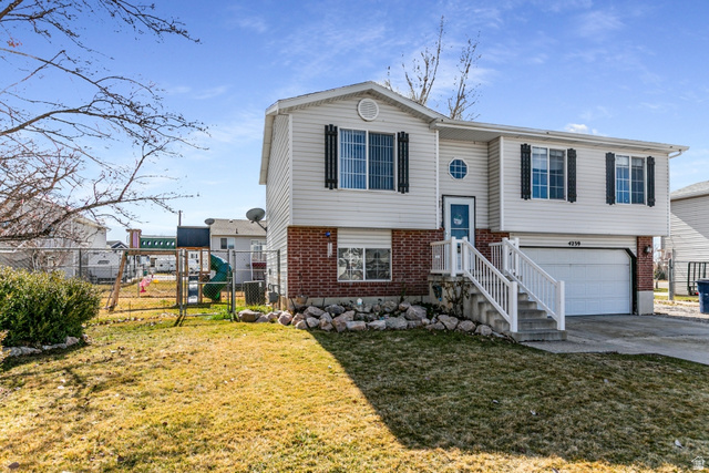 4239 West 5325th Street South Roy, UT 84067 - Photo 19 of 26 Split foyer home featuring brick siding, a gate, a garage, and concrete driveway