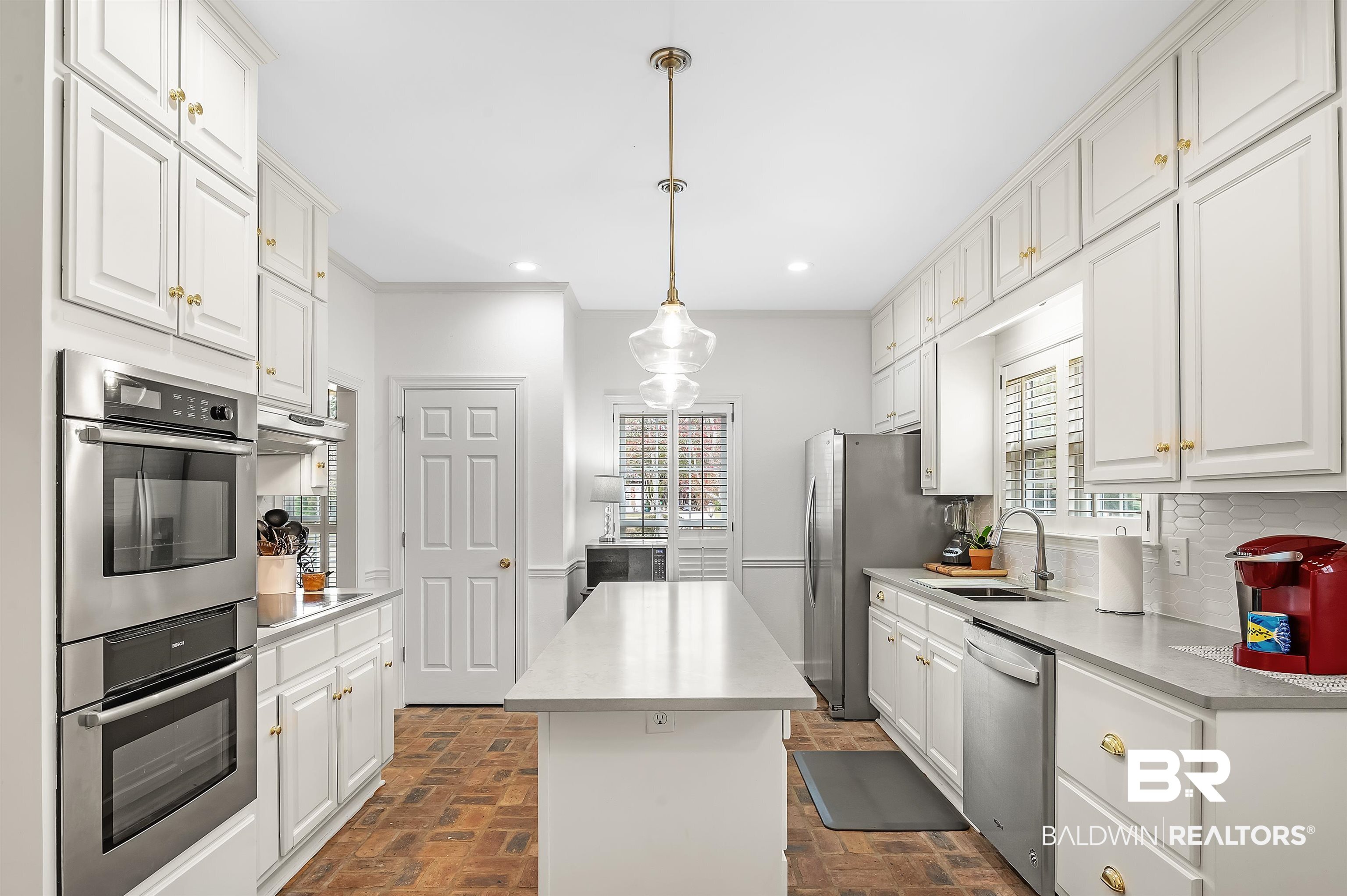 8915 Bay Point Drive Elberta, AL 36530 - Photo 41 of 74 Kitchen with tasteful backsplash, white cabinets, brick floor, stainless steel appliances, and a sink