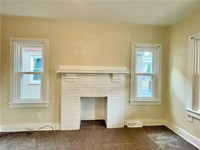 a view of an empty room with a fireplace and a window