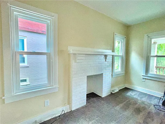 a view of an empty room with a fireplace and a window