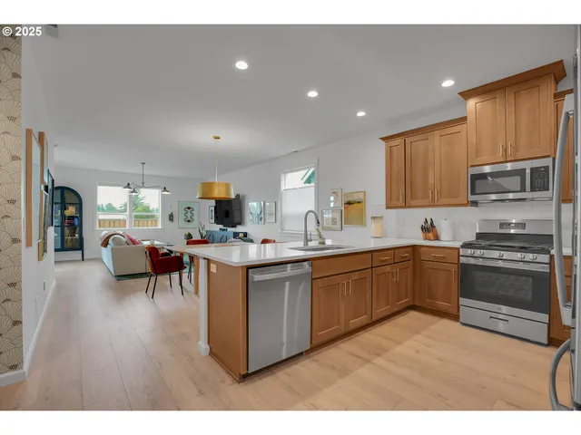 a kitchen with stainless steel appliances granite countertop a stove top oven a sink dishwasher a dining table and chairs with wooden floor