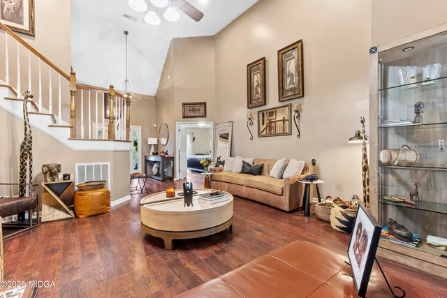 a living room with couches a fireplace and kitchen view with wooden floor