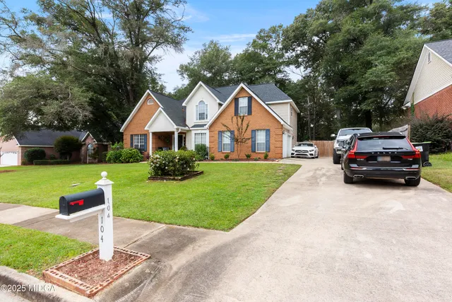 a view of a yard in front of a house with large windows