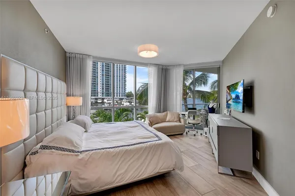 a bedroom with a large bed and a flat tv screen