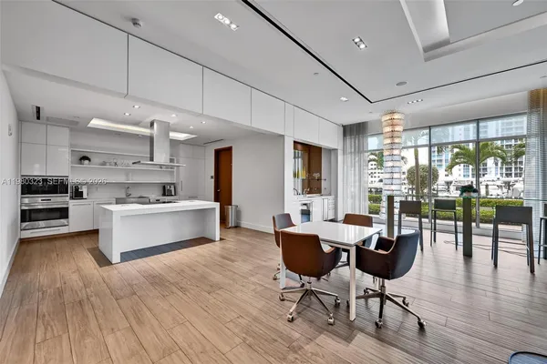 a large white kitchen with lots of furniture and stainless steel appliances