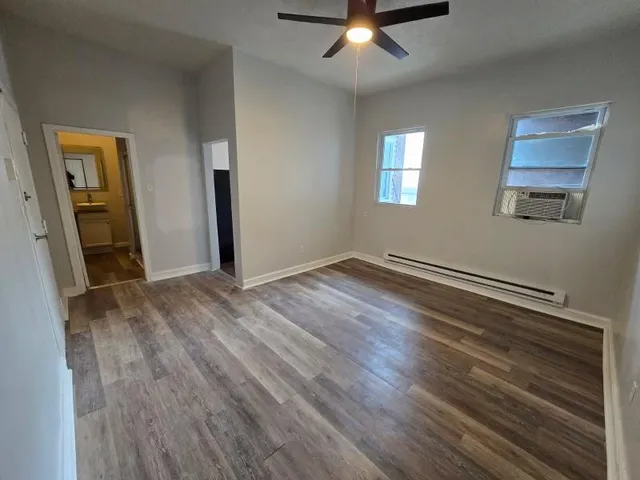 a view of an empty room with wooden floor and a window