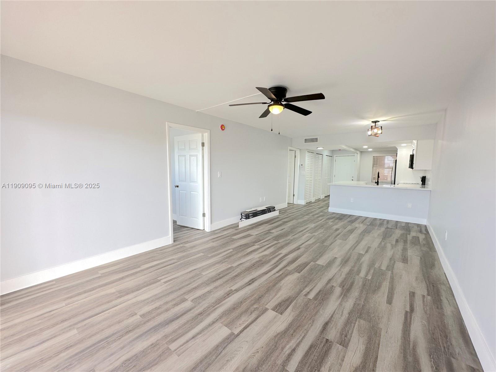3110 North Pine Island Road, Unit 408 Sunrise, FL 33351 - Photo 7 of 18 a view of a big room with wooden floor and a ceiling fan
