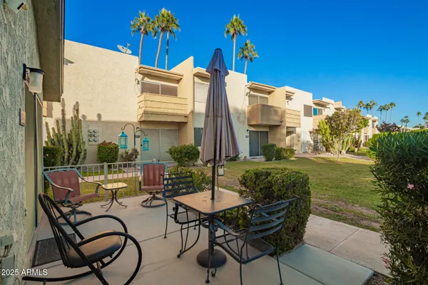 a patio with table and chairs and potted plants