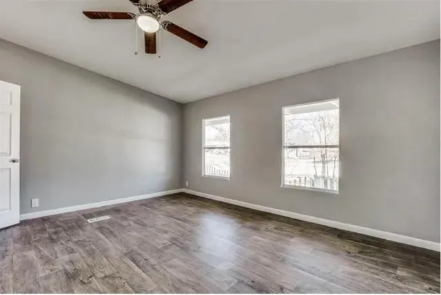 a view of an empty room and window with a ceiling fan