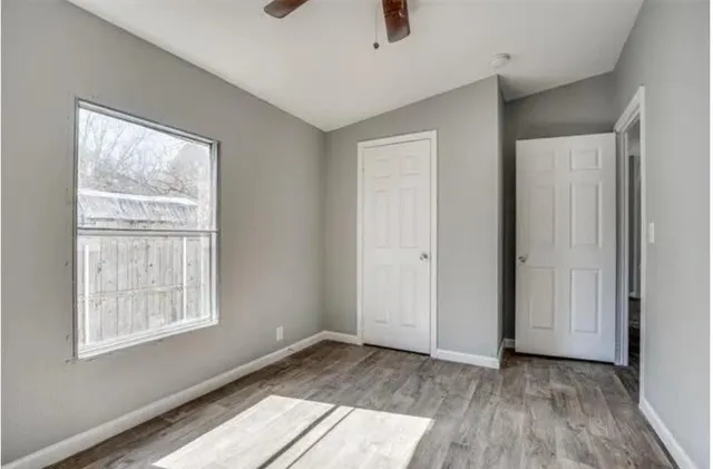 an empty room with wooden floor and windows