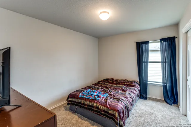 a bedroom with a bed and a flat tv screen on the dresser