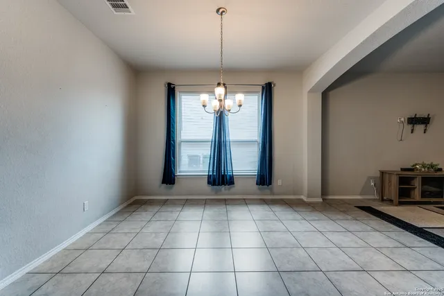 a view of an empty room with window and chandelier fan
