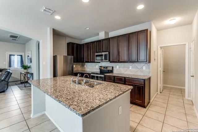a kitchen with kitchen island granite countertop a stove refrigerator and cabinets