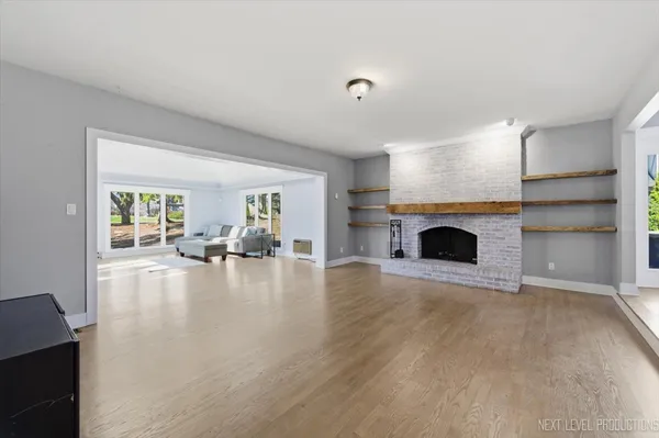 a view of empty room with fireplace and wooden floor