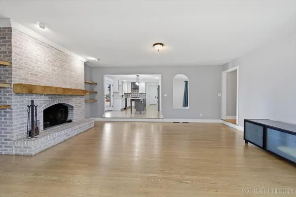 a view of empty room with fireplace and kitchen view