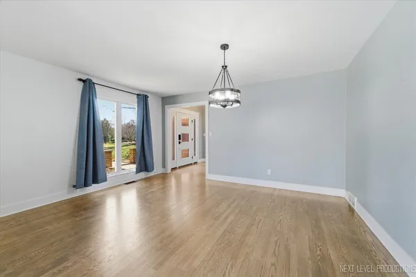 a view of a room with wooden floor chandelier and windows